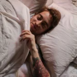 Man resting peacefully in bed under soft blankets, illustrating healthy sleep and restorative rest.